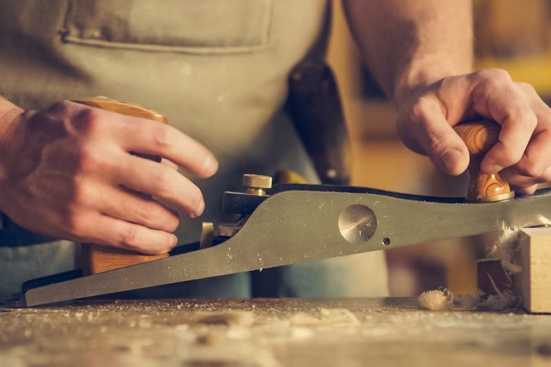 Charpentier travaillant une pièce de bois au rabot