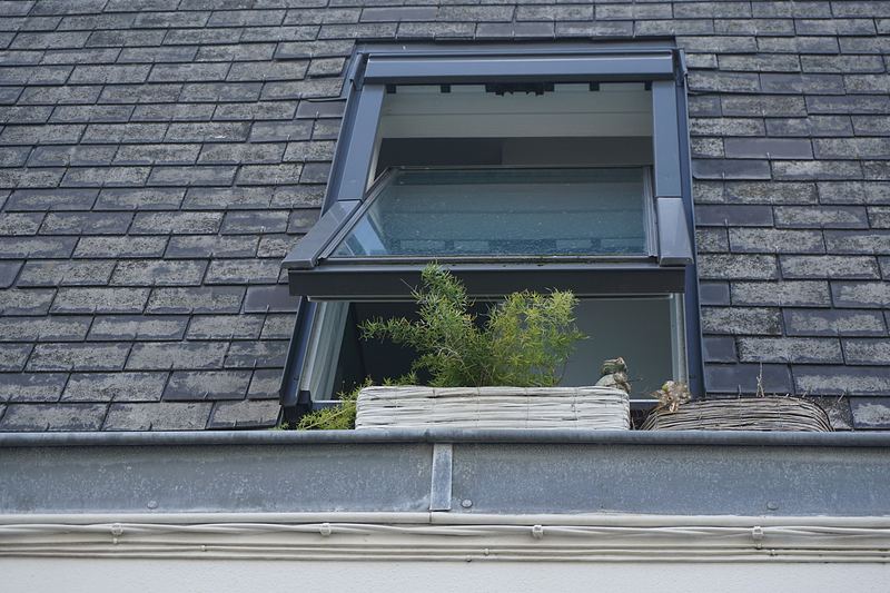 Fenêtre de toit ouverte posée sur une couverture en ardoise